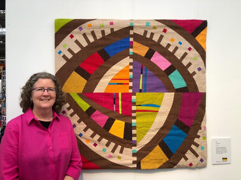 Cindy Grisdela standing next to her Confetti quilt